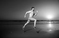 Young athletic and fit american sport man doing running workout on sunset at the beach training jogging barefoot in Royalty Free Stock Photo