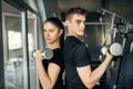 Young athletic fitness trainers.Active couple training together.Dumbbell workout.Fit woman and man side by side,partner training.
