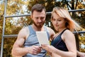 Young athletic girl and bearded man browsing the internet on tab