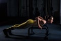 Young athletic girl in yellow tight sports uniform doing horizontal push-ups with bars in gym Royalty Free Stock Photo