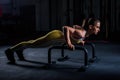 Young athletic girl in yellow tight sports uniform doing horizontal push-ups with bars in gym Royalty Free Stock Photo