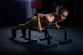 Young athletic girl in yellow tight sports uniform doing horizontal push-ups with bars in gym Royalty Free Stock Photo
