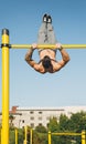 Young athletic man doing gymnastics on bars at a calisthenics park