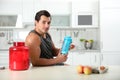Young athletic man with ingredients for protein shake in kitchen