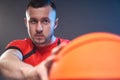 Young athletic man prepared for throwing basketball ball pointing it to the target on cold grey background Royalty Free Stock Photo