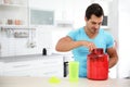 Young athletic man  protein shake in kitchen, space for text Royalty Free Stock Photo