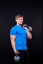 Young athletic man standing with kettlebells on