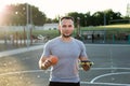 Young athletic man in a t-shirt holds a Burger and an Apple in the background of the stadium Royalty Free Stock Photo