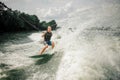 Young and athletic man wakesurfing on the board against the sky Royalty Free Stock Photo
