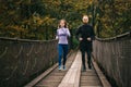 Young athletic man and woman performing a morning run on a suspension bridge. Royalty Free Stock Photo