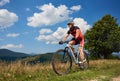 Young athletic professional sportsman biker riding bike down the hill on distant mountains Royalty Free Stock Photo