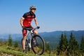 Young athletic professional sportsman starting cycling bike on top of hill