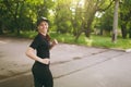 Young athletic smiling beautiful brunette girl in black uniform and cap training, doing sport exercises and running Royalty Free Stock Photo