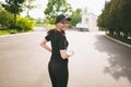 Young athletic smiling beautiful brunette girl in black uniform and cap training, doing sport exercises and running Royalty Free Stock Photo