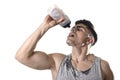 Young athletic sport man thirsty drinking water holding bottle pouring fluid on sweaty face