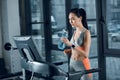 young athletic sportswoman drinking water while jogging on treadmill