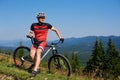 Young athletic tourist biker resting at his bike on mountain hill Royalty Free Stock Photo