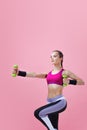 Young athletic woman, in a bright sports top, with green dumbbells.