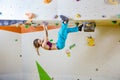 Young woman climbing upside down in bouldering gym