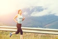 Young athletic woman jogging on road in mountains