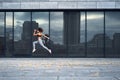 Young athletic woman jumping while making running training at urban city location with big mirror windows on background Royalty Free Stock Photo