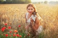 Young athletic woman, kneeling, holding Jack Russell terrier puppy on her hands, some red poppy in foreground and sunset lit wheat Royalty Free Stock Photo