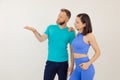 Young athletic woman and man in blue sportswear standing and pointing by hand, white background. Keeping fit by fitness Royalty Free Stock Photo