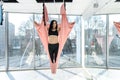 Young athletic woman practices relax yoga, stretching in an exercise using a hammock afret hard workday