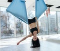 Young athletic woman practices relax yoga, stretching in an exercise using a hammock afret hard workday