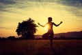 Young athletic woman practicing yoga on a meadow at sunset