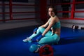 Young athletic woman sitting near lying boxing gloves and helmet Royalty Free Stock Photo