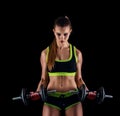 Young athletic woman in sportswear with dumbbells in studio against black background. Ideal female sports figure. Royalty Free Stock Photo