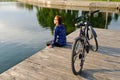 Young athletic woman in sportswear sits next to a bicycle Royalty Free Stock Photo