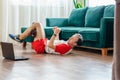 A young athleticman in red shorts is doing exercises on a foam roller using notebook laptop. Works out of the muscles Royalty Free Stock Photo