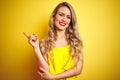 Young attactive woman wearing t-shirt standing over yellow isolated background with a big smile on face, pointing with hand and Royalty Free Stock Photo