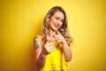 Young attactive woman wearing t-shirt standing over yellow isolated background pointing fingers to camera with happy and funny Royalty Free Stock Photo