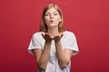 Young attarctive woman blowing kiss at camera on the red background