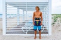 Young attceractive guy surfer stands on the beach looking out into the distance, Royalty Free Stock Photo