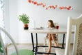 Young attentive girl is studying, looking at laptop, writing in notebook Royalty Free Stock Photo