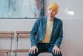 Young attractive adult bearded man hipster in yellow hat sitting on chair and looking at camera, real people lifestyle Royalty Free Stock Photo