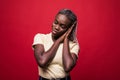 Young attractive African American with an afro hairstyle with delight looks left to the empty space, her hands touch her face,