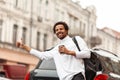 Young attractive African man hailing cab taxi on city street, raises his hand Royalty Free Stock Photo