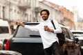 Young attractive African man hailing cab taxi on city street, raises his hand Royalty Free Stock Photo