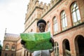 Young attractive afro american female tourist strolling on city streets with map searching right direction to popular showplaces.