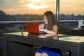 Young attractive Asian Chinese business woman working online with laptop computer from rooftop sky bar on beautiful sunset as Royalty Free Stock Photo