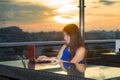 Young attractive Asian Chinese business woman working online with laptop computer from rooftop sky bar on beautiful sunset as Royalty Free Stock Photo