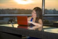 Young attractive Asian Korean business woman working online with laptop computer from rooftop sky bar on beautiful sunset as Royalty Free Stock Photo