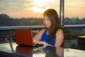 Young attractive Asian Korean business woman working online with laptop computer from rooftop sky bar on beautiful sunset as Royalty Free Stock Photo