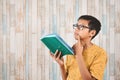 Young attractive asian male student pondering while holding a book Royalty Free Stock Photo