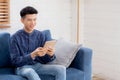 Young attractive asian man resting using browsing tablet computer on sofa at home. Royalty Free Stock Photo